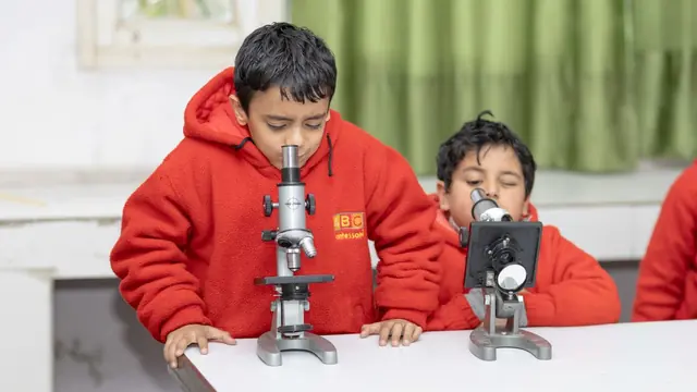 Two pupils looking through microscopes in a science lab