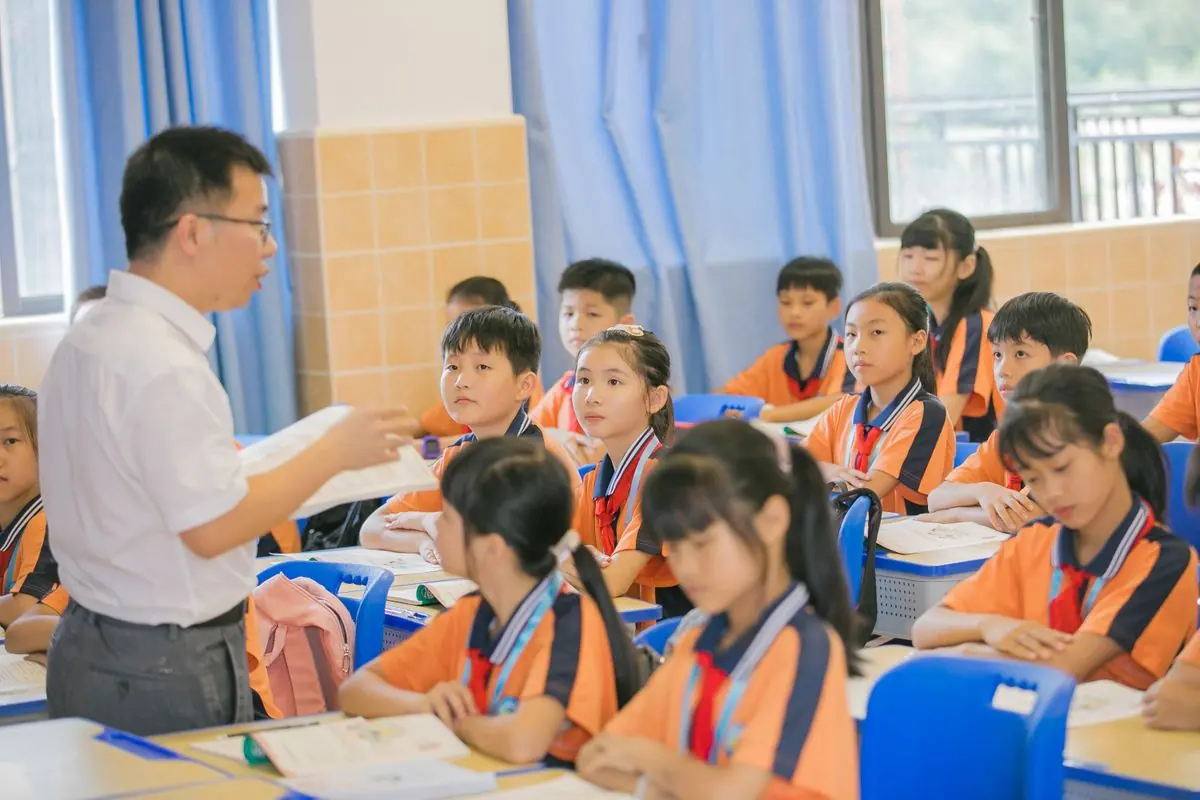 A teacher working with a group of primary pupils at their desks