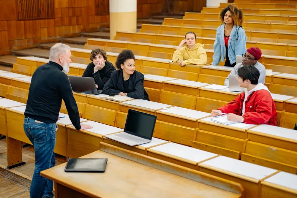 Students and a lecturer discussing work in a tiered lecture theatre