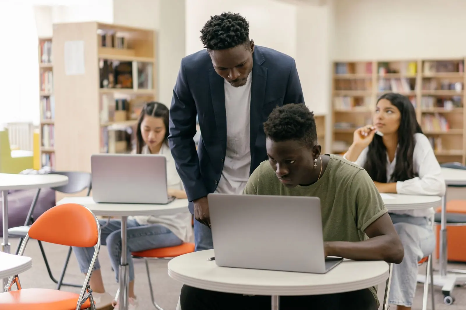 Students and a tutor collaborating around a laptop in a library
