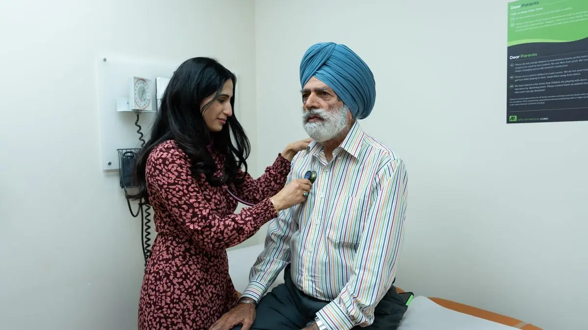 A doctor listening to an older patient's chest with a stethoscope