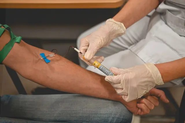 A gloved clinician taking a blood sample from a patient's arm