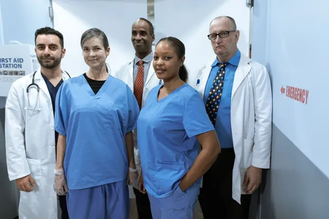 A smiling medical team in scrubs and white coats