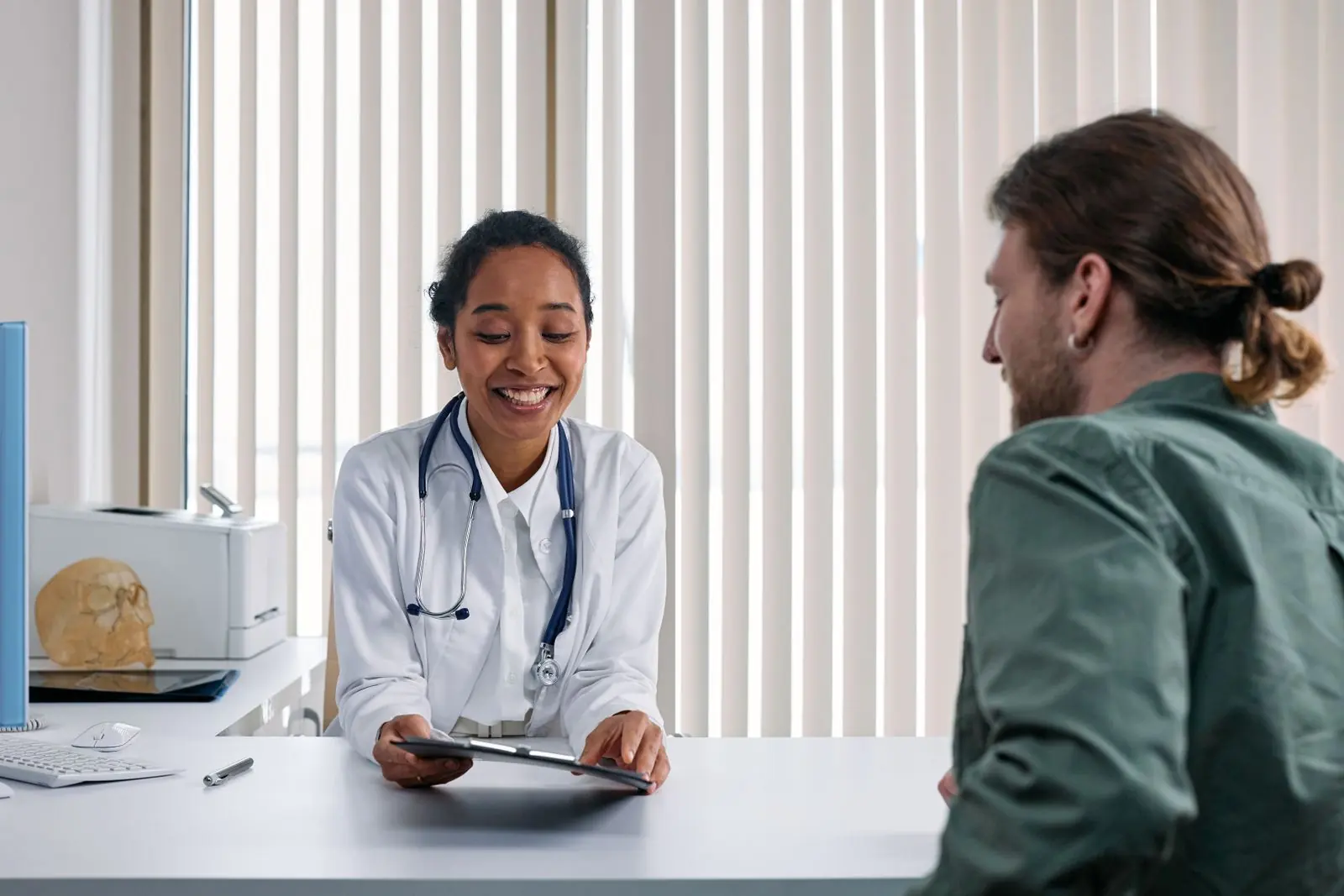 A smiling doctor talking with a patient across a consultation desk