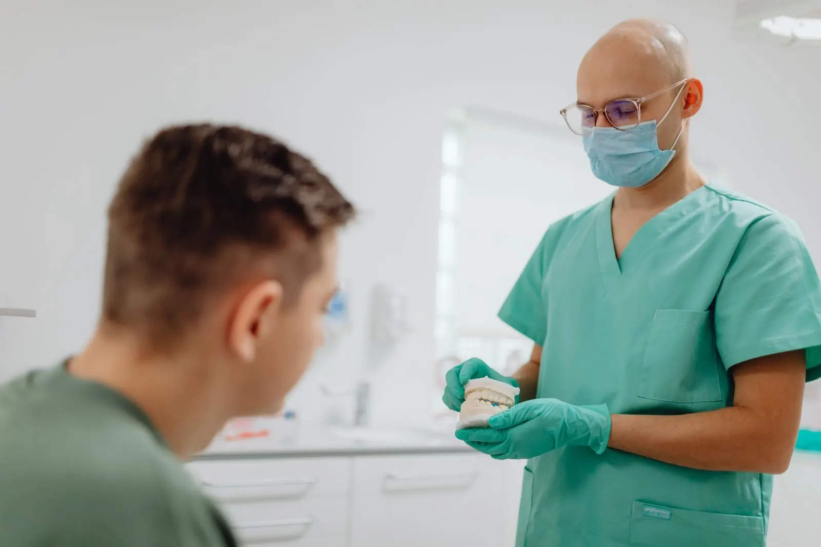 A dentist discussing a dental model with a seated patient