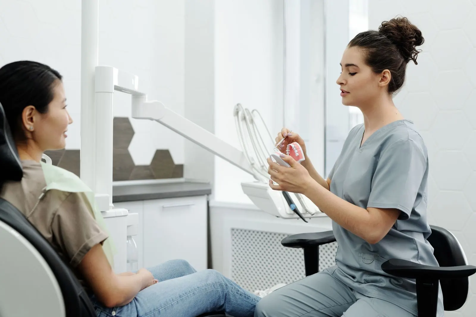 A dental professional explaining a tooth model to a patient