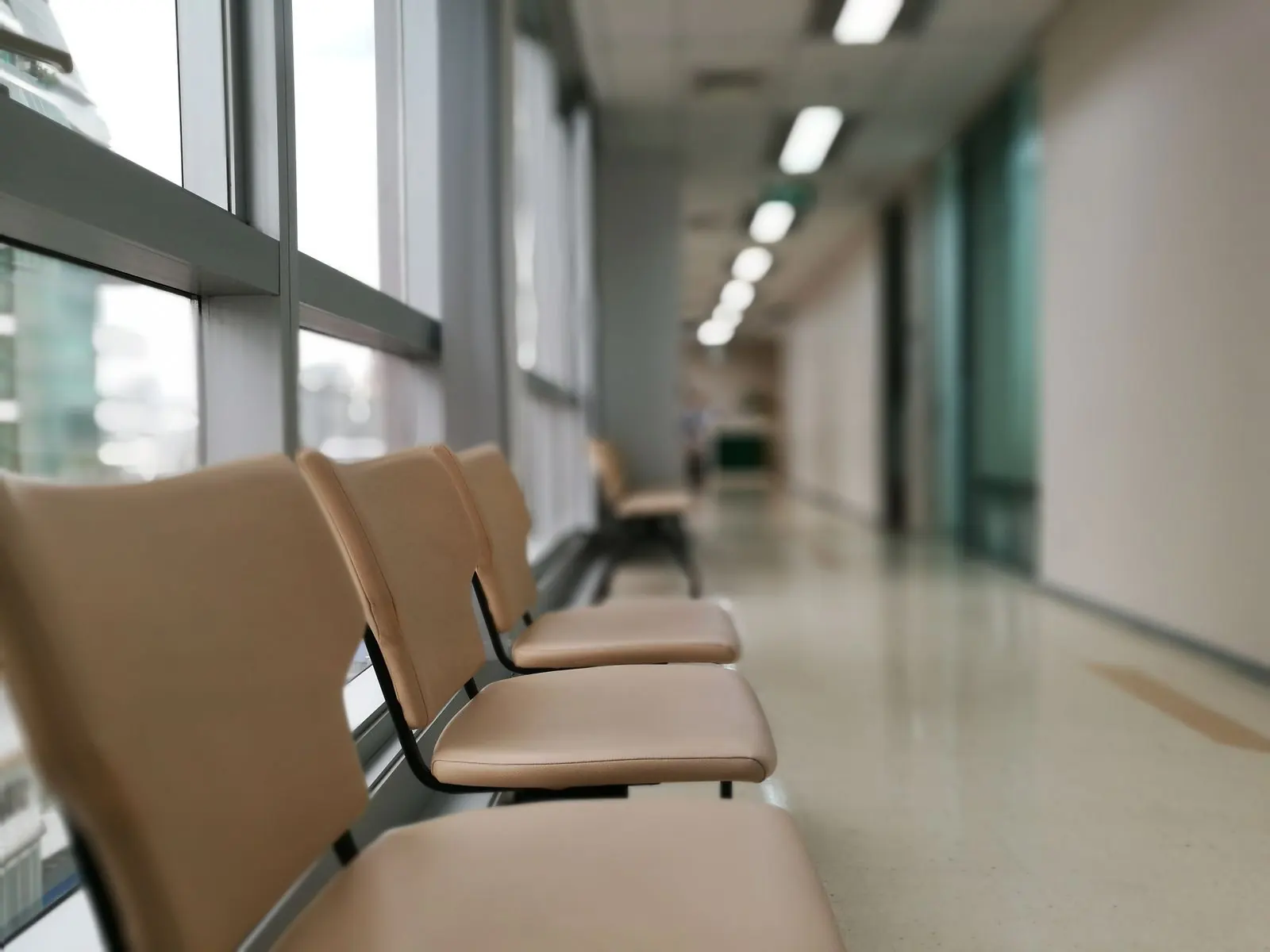 Waiting chairs beside tall windows in a bright clinic corridor