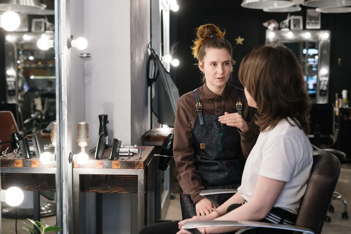 A hair stylist discussing a look with a seated client