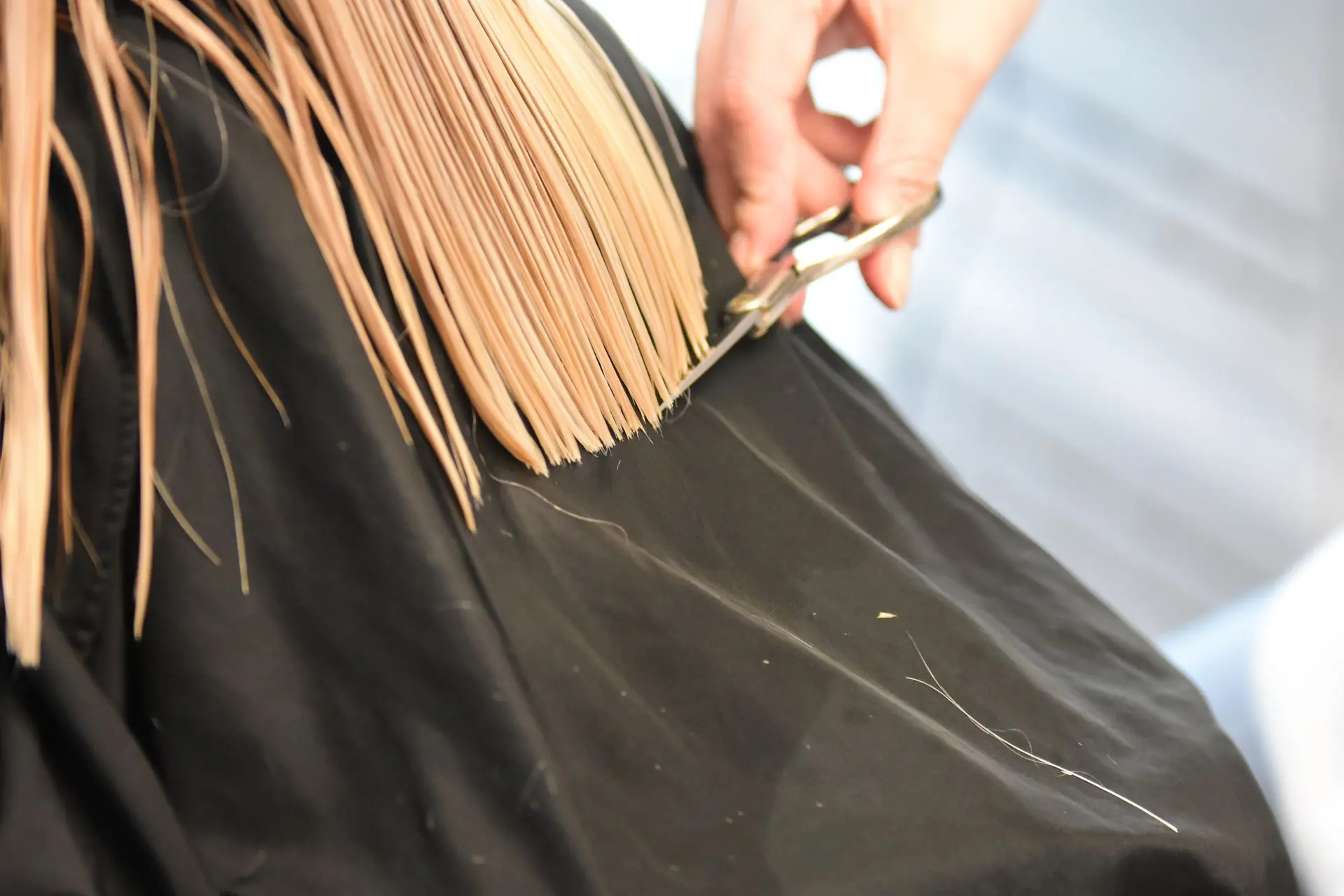 Hair stylist cutting a section of blonde hair