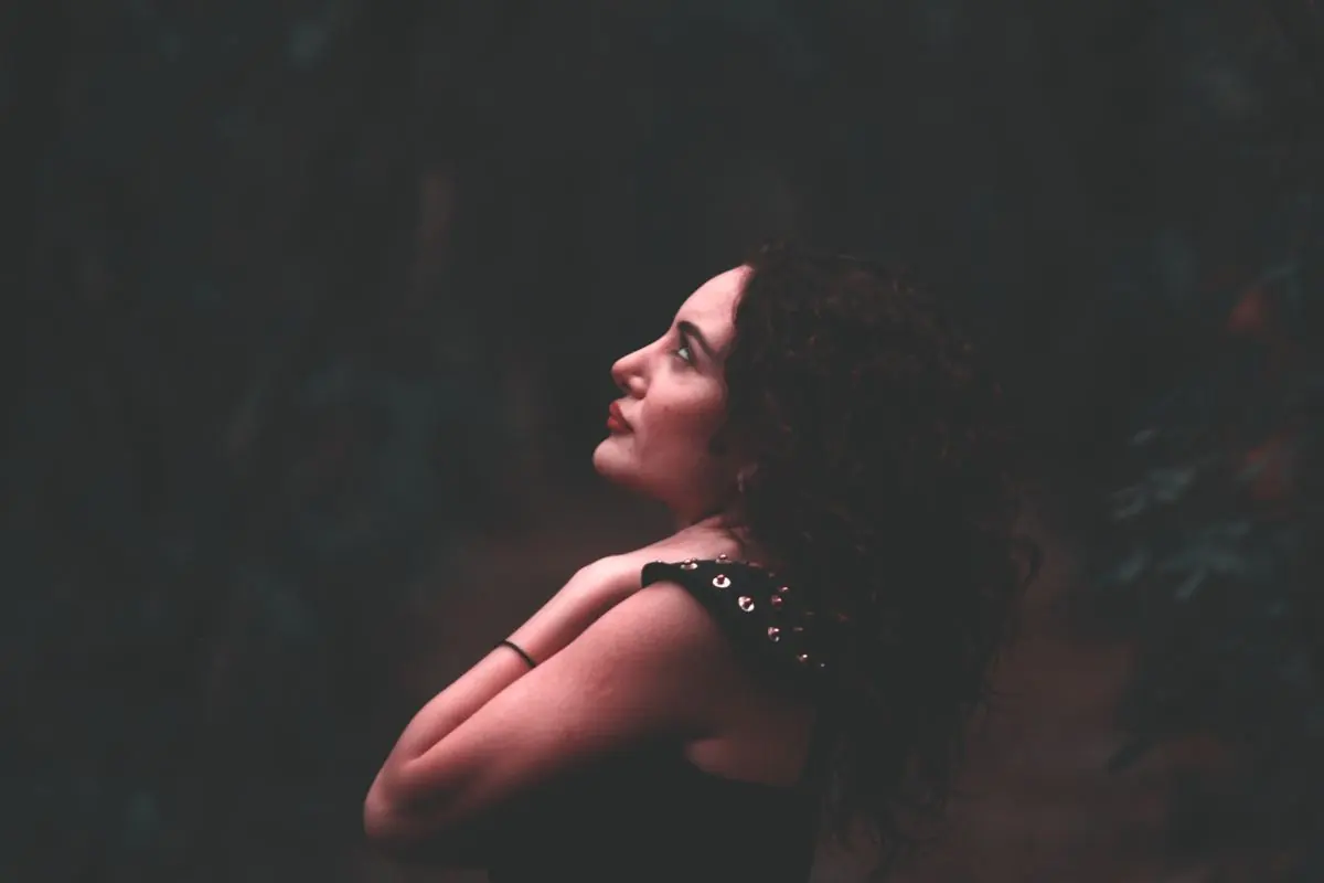 A person with curly hair in a softly lit profile portrait