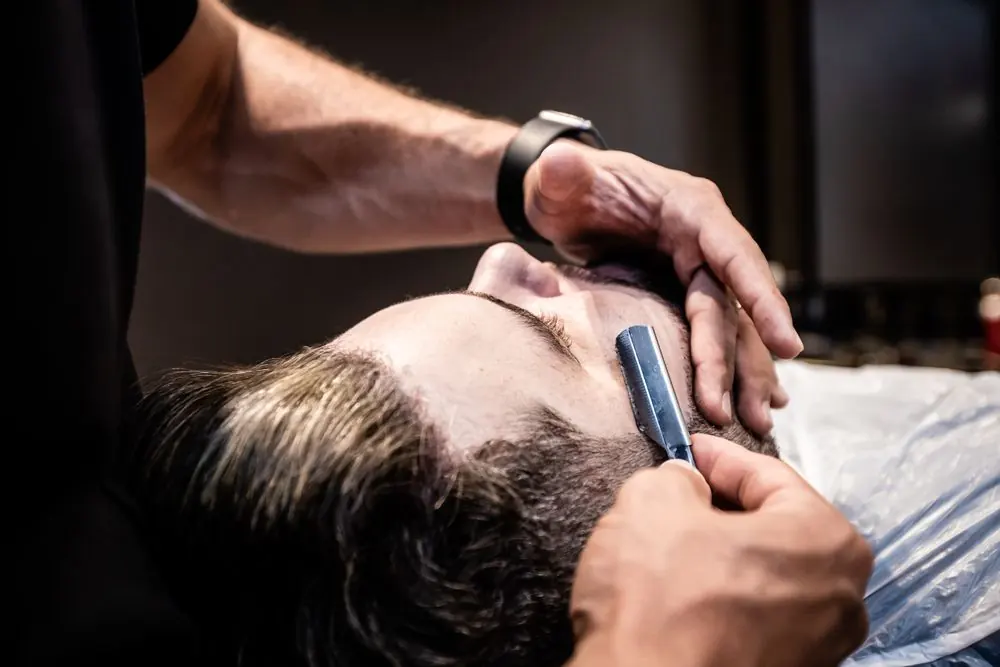 A barber giving a client a careful straight-razor shave