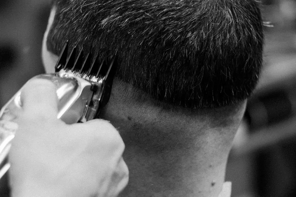 Close detail of clippers shaping a short fade haircut