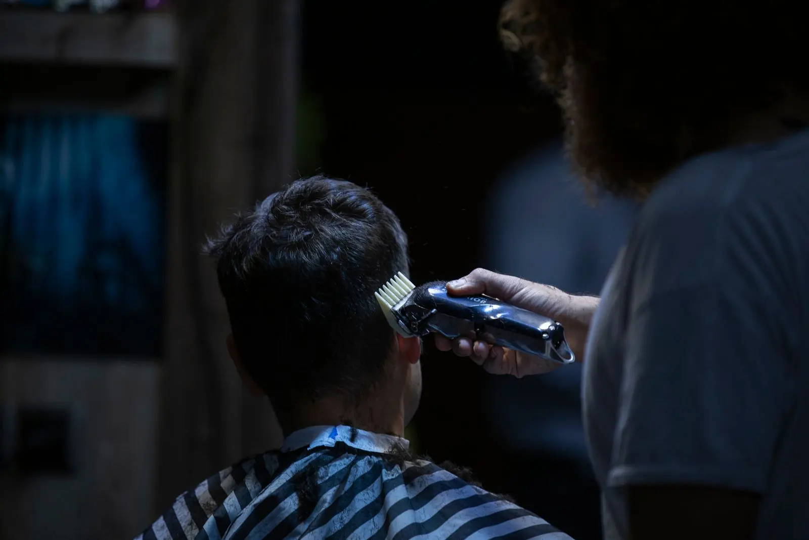 A barber shaping a short haircut with clippers