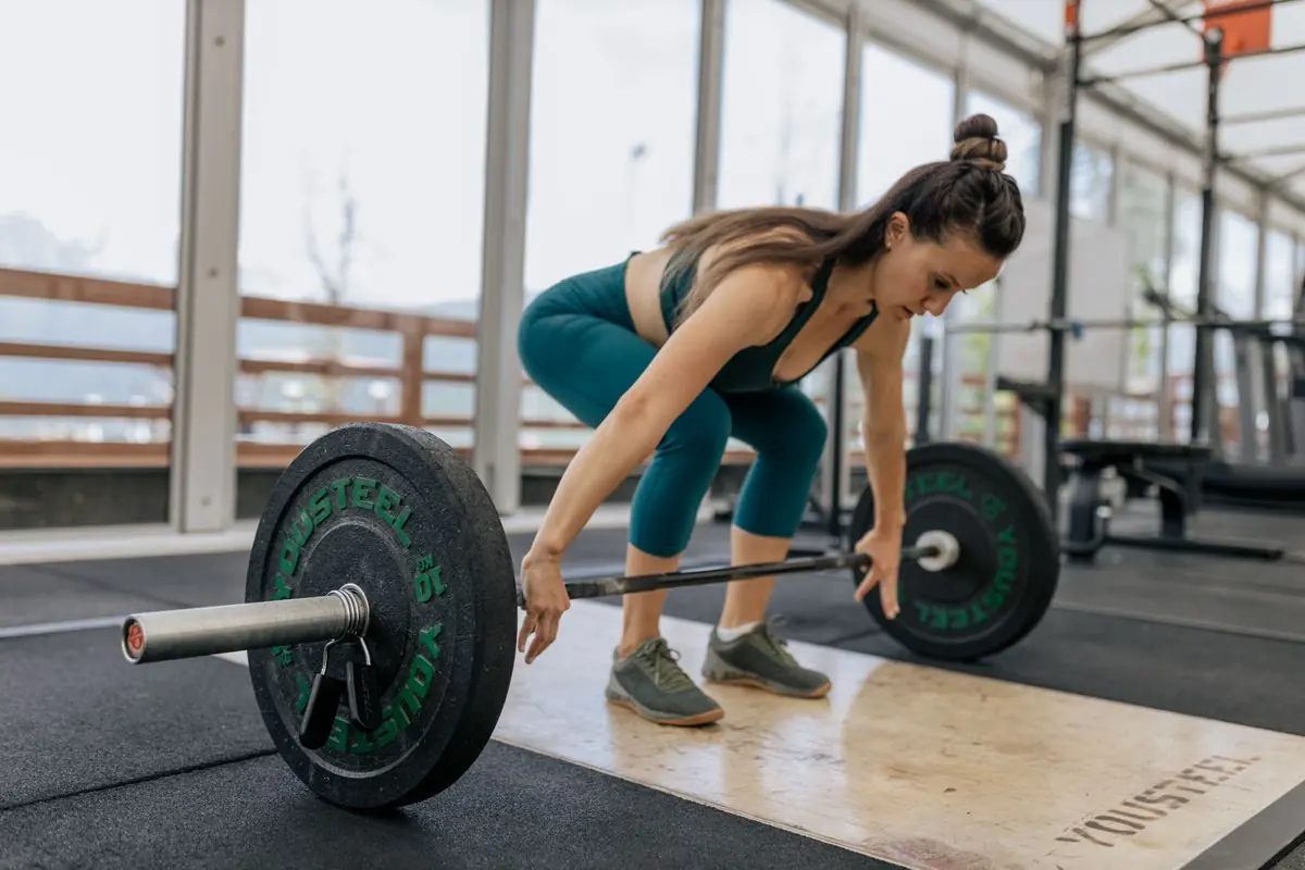 A woman setting up for a barbell deadlift on a lifting platform