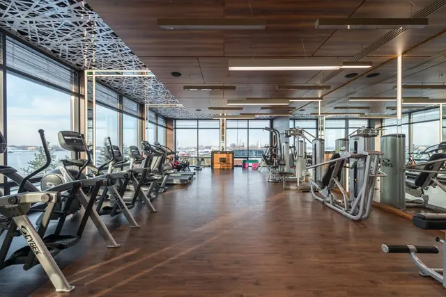 A long gym floor with machines along tall windows