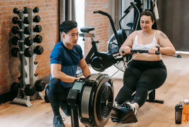 Two people training on rowing machines side by side