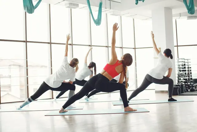 A bright studio with people stretching during a class