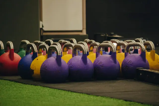 Colourful kettlebells lined up on artificial turf