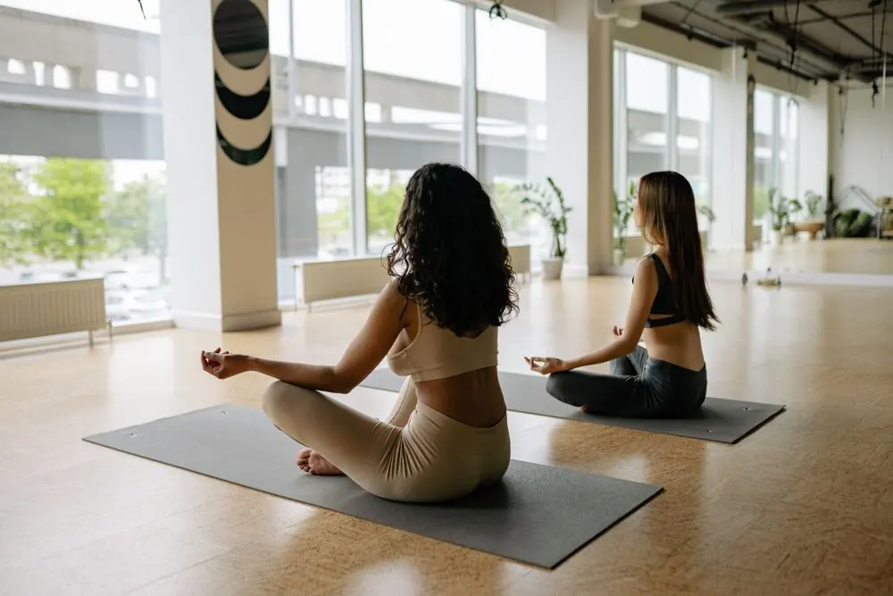 Two participants sitting quietly on mats in an airy studio
