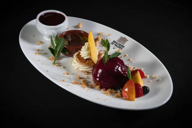 A plated chocolate dessert with cherry sauce on a white plate