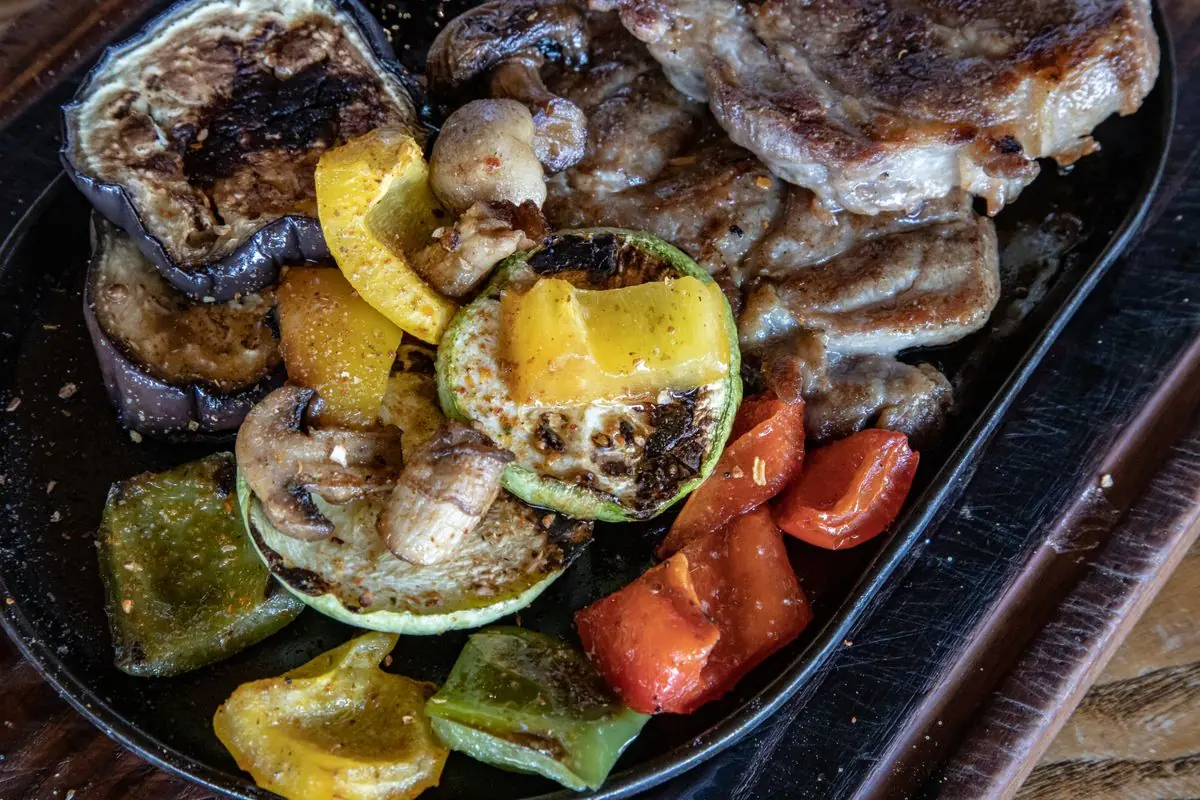 A platter of charred peppers, tomatoes and grilled meat