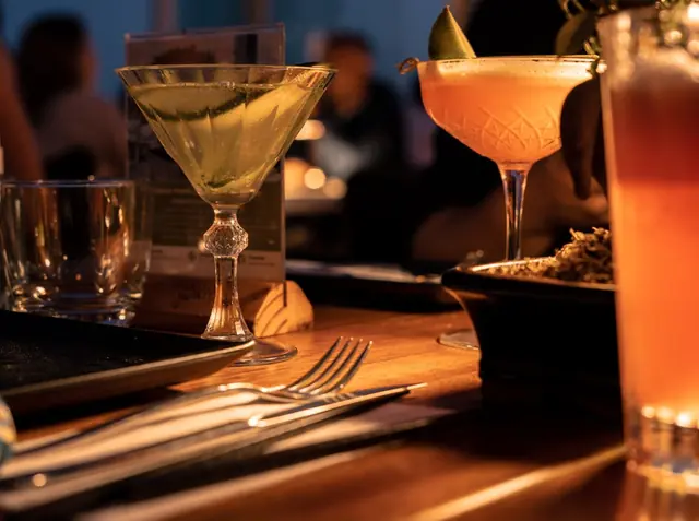 Cocktails glowing in candlelight on a bar counter