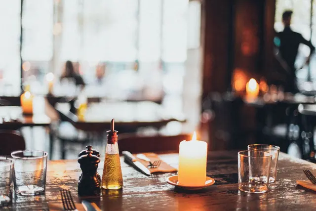A candle-lit table set with glasses in a warm dining room