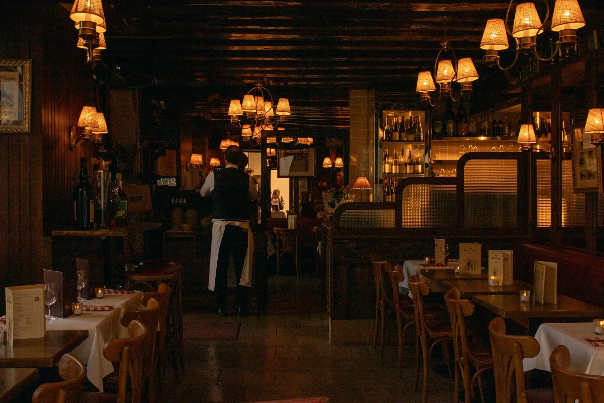 A softly lit restaurant dining room with wooden tables and warm lamps