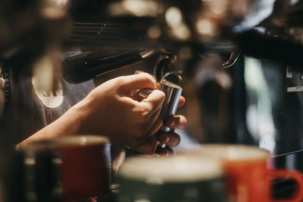 A barista preparing an espresso portafilter at the coffee machine