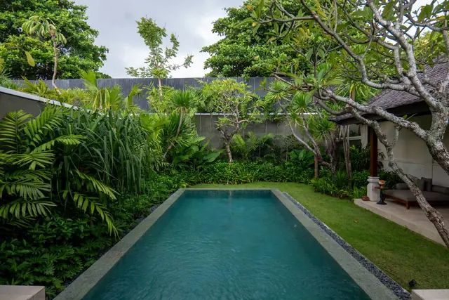 A long private pool set in a walled tropical garden beside a villa veranda