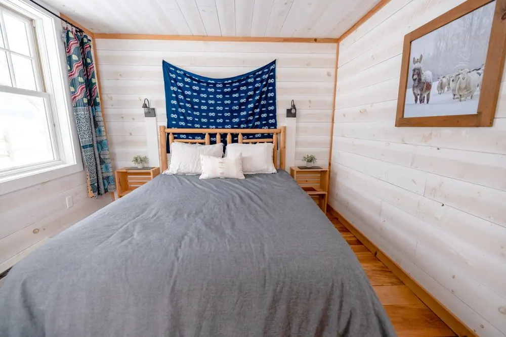 Light cottage bedroom with white timber walls, grey bedding and blue textile detail