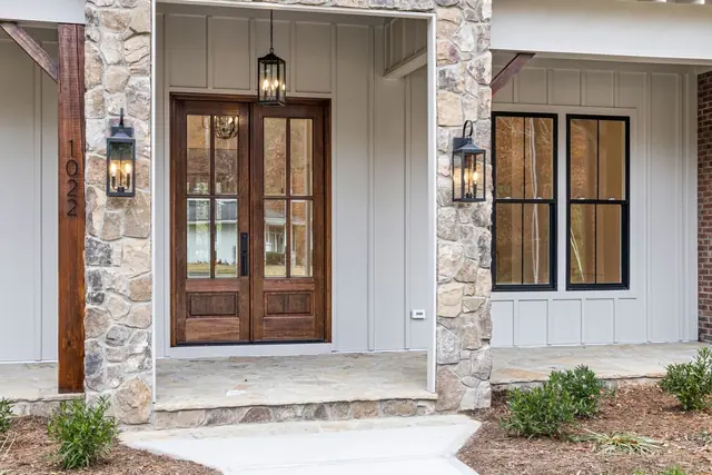 A stone-framed porch with glazed timber double doors and lanterns on each side