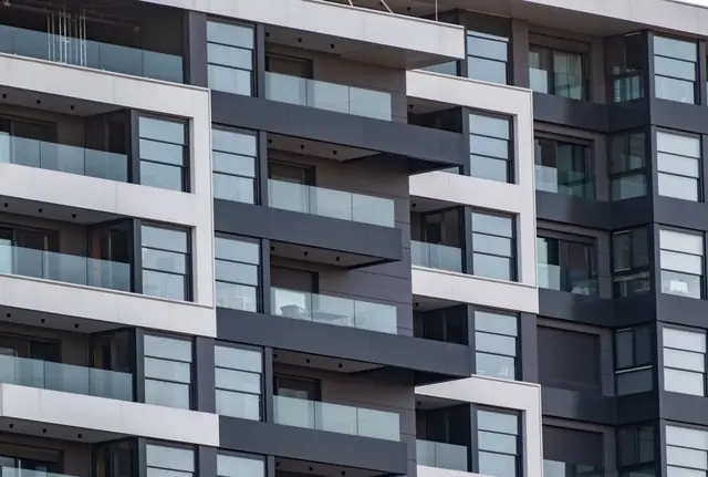 A modern apartment building with grey and white balconies and tall glass doors