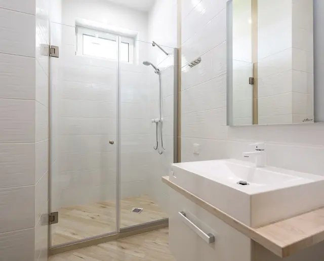 A clean white bathroom with a glass shower and basin