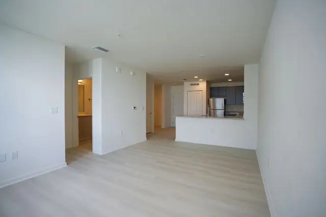 An empty, bright apartment with an open-plan kitchen