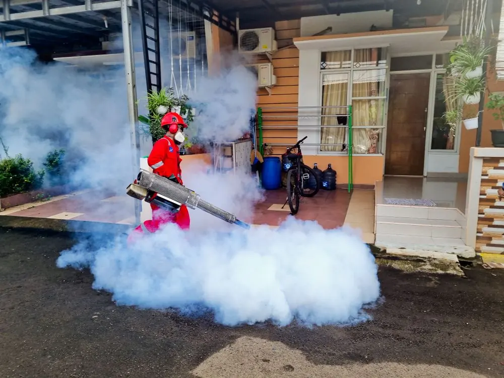Pest-control worker using fogging equipment outdoors