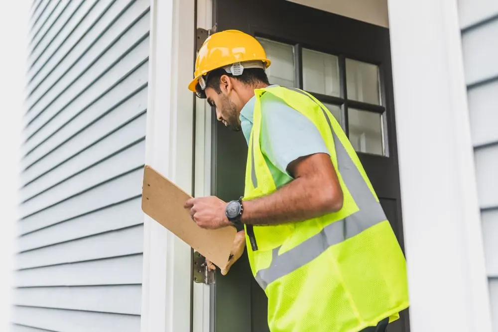 Home inspector reviewing notes near an exterior window