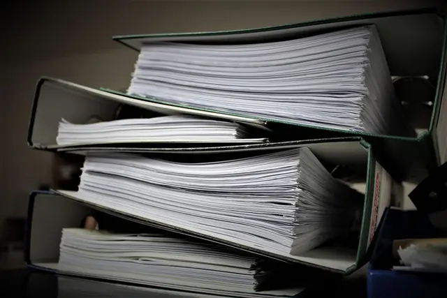 Ring binders stacked on their sides, packed with printed working papers