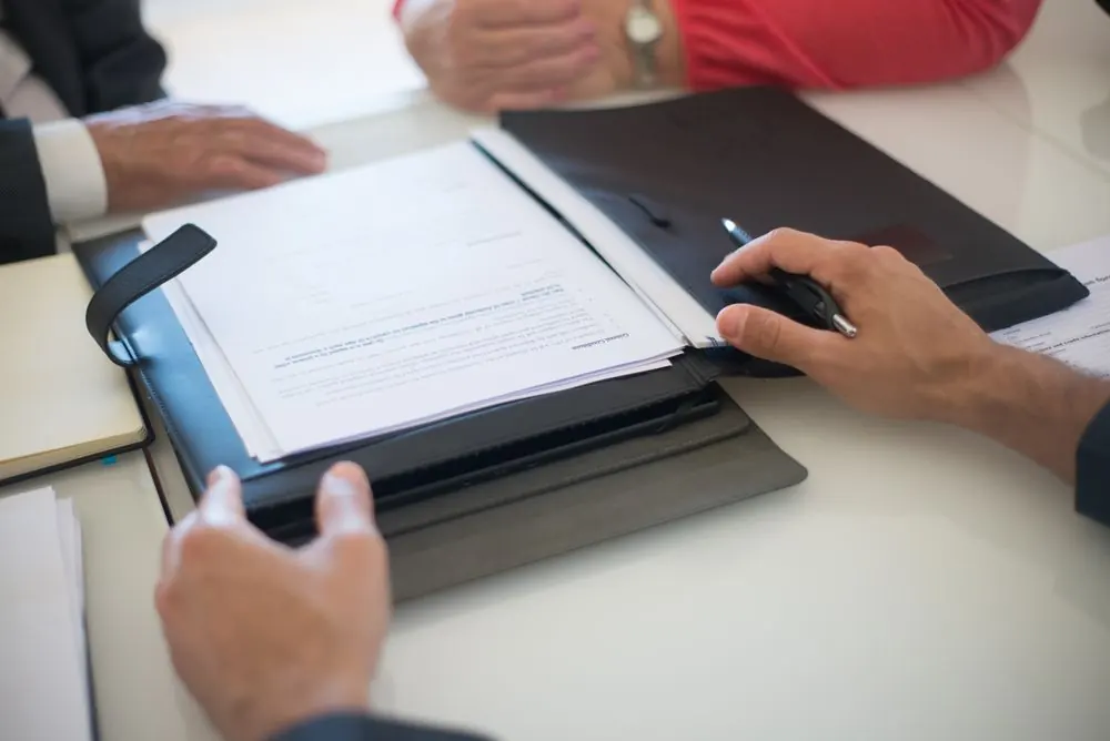 People reviewing paperwork on a desk with a tablet