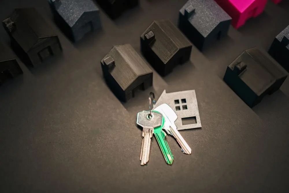 House keys beside miniature house shapes on a dark surface