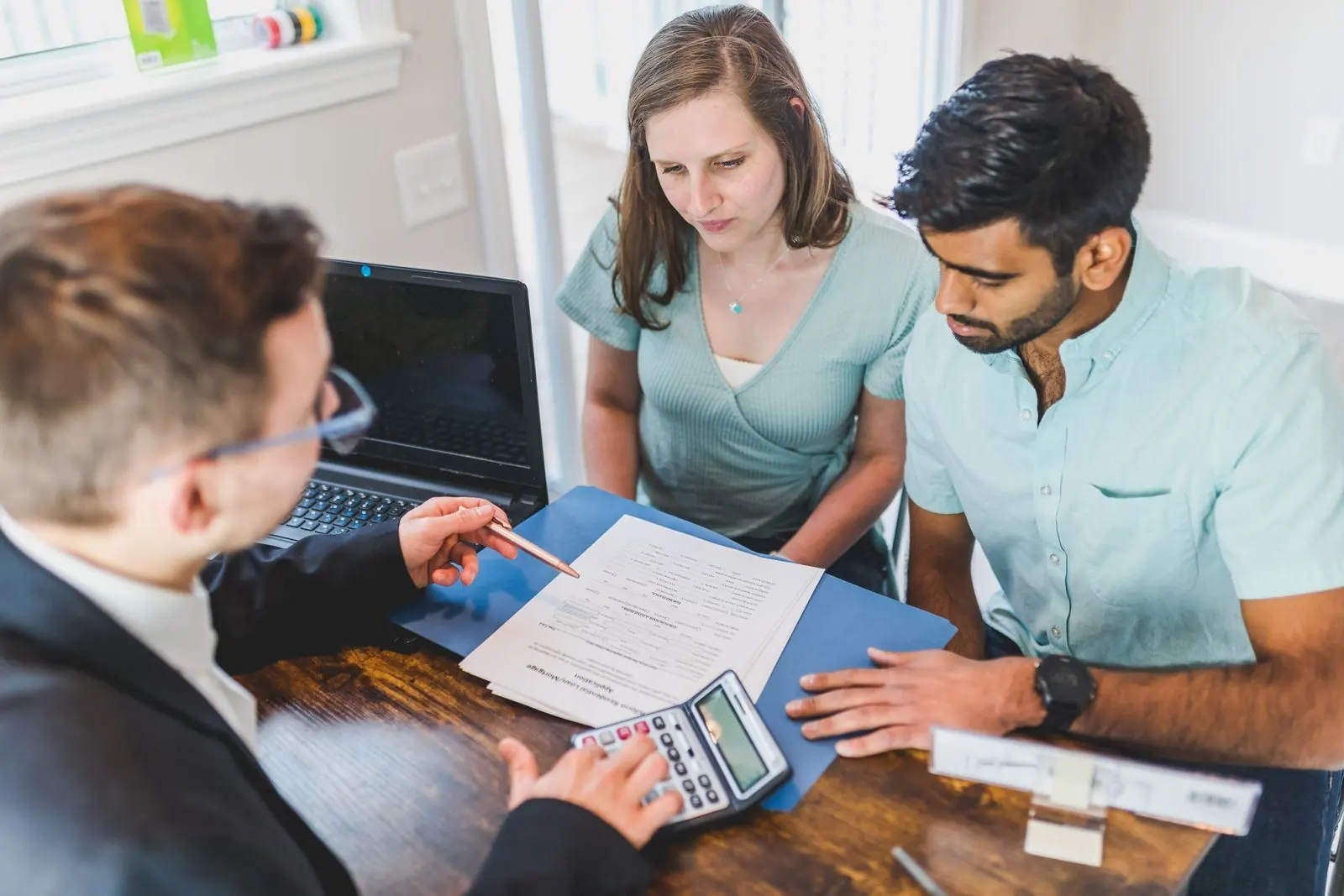 A couple discussing documents with an adviser at a table