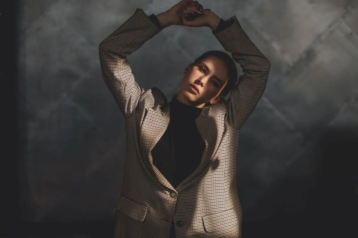 A model in a beige suit posing against a dark textured wall