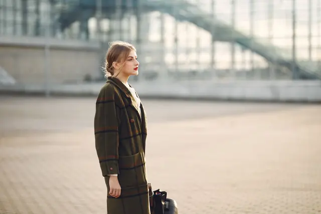 A model in a long olive coat on a city street
