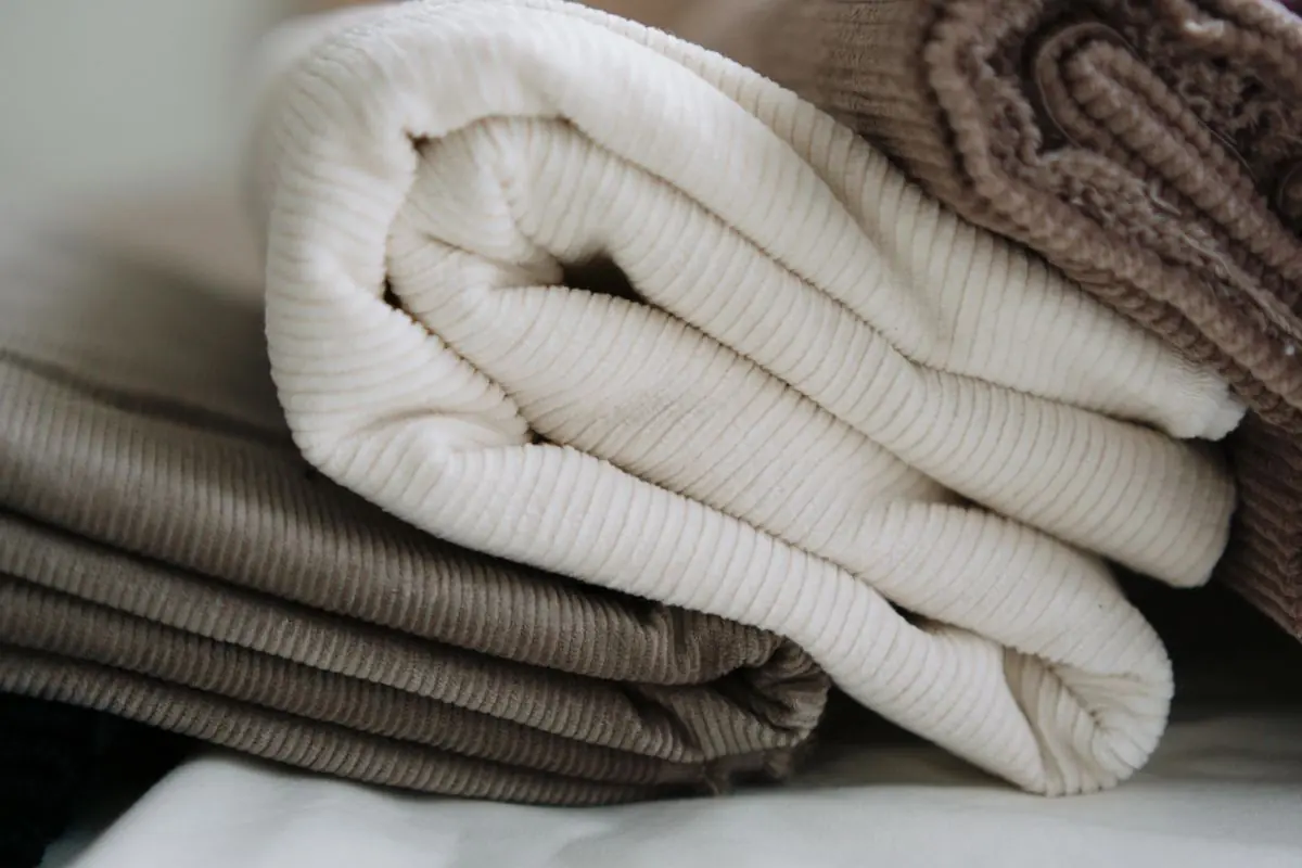 Folded cream and taupe fabrics stacked on a shelf